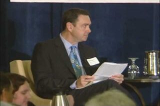 Man reading notes at conference panel