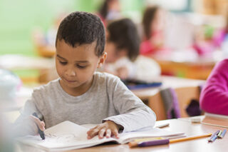 African American Schoolboy Drawing On A Class At School.