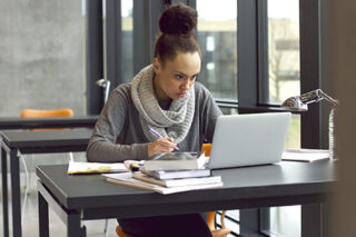 Young Female Student Taking Notes For Her Study