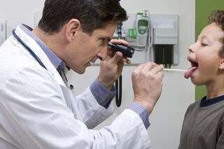 Pediatric Doctor Looking In Patient’s Mouth