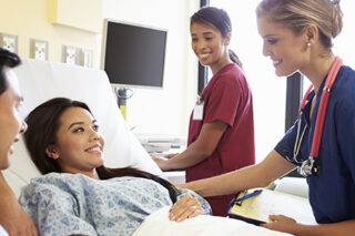 Medical Team Meeting With Couple In Hospital Room