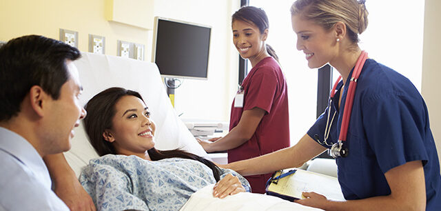 Medical Team Meeting With Couple In Hospital Room