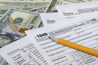 Pencil With Tax Form On US Dollarbills Background
