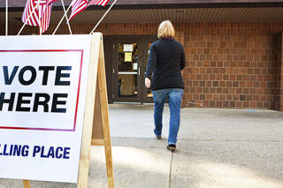 Woman Voter Entering Voting Polling Place For USA Government Election