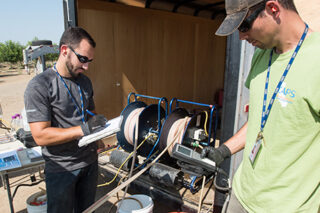 Fish and Wildlife Scientific Aid Brian Bettencourt (left) records data while Environmental Scientist Evan MacKinnon (right) reads off water quality parameters from a multi-parameter water quality meter at a well in Sutter County, California for the Department of Water Resources