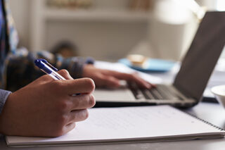 Teenage boy working at a desk in his bedroom, close up