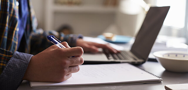 Teenage boy working at a desk in his bedroom, close up