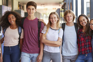 Teenage classmates standing in high school hallway