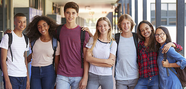 Teenage classmates standing in high school hallway