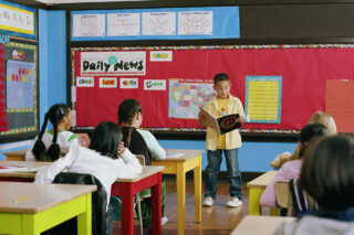 photo - Boy Reading in Front of Class