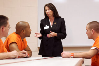 Three Inmates Listen To A Woman Discuss Options And Privileges That They Might Earn While Serving Time In Prison.