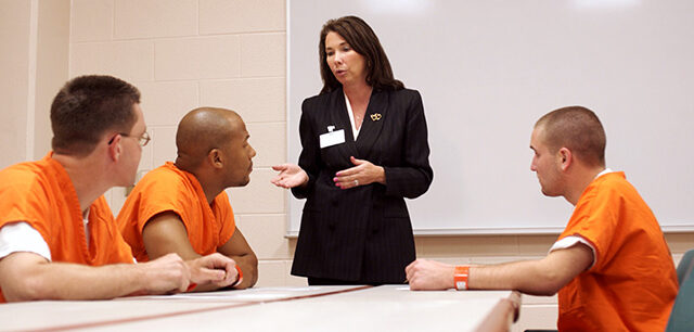 Three Inmates Listen To A Woman Discuss Options And Privileges That They Might Earn While Serving Time In Prison.