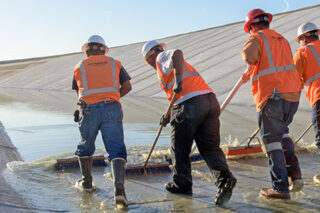 Contracts in orange vests with an assistance with a California Department of Water Resources worker, perform final close-out repairs at the Pool 30 project.