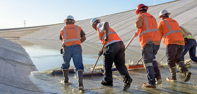 Contracts in orange vests with an assistance with a California Department of Water Resources worker, perform final close-out repairs at the Pool 30 project.