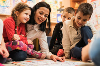 Happy teacher with a group of kids in a preschool.