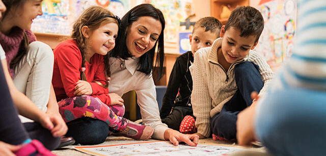 Happy teacher with a group of kids in a preschool.
