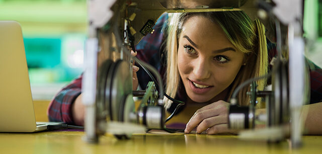 Happy Woman Examining A New Robot In Laboratory.