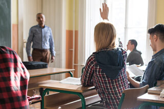 Lone girl raising hand in classroom