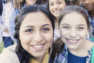 Diverse Group Of Teens Looking At Camera Taking Selfie At High School