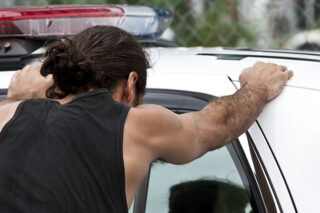 photo - Man with His Hands on Top of a Police Car