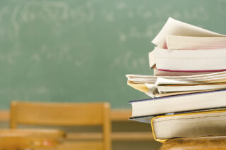 photo - Pile of Books on a Desk in a Classroom