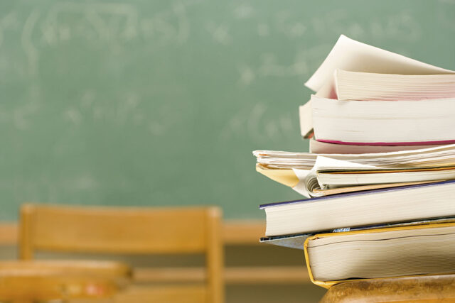 photo - Pile of Books on a Desk in a Classroom