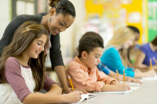 photo - Students at Long Table Writing with Pencils