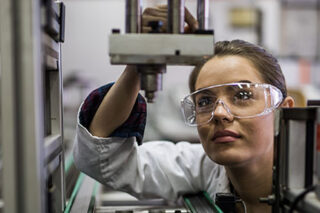 photo - Woman Examining Machine Part on a Production Line