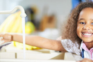 little girl turning on water faucet