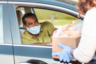 Man In Car Wears Mask While Receiving Box Of Food