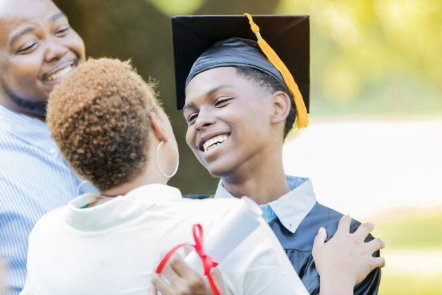 photo - High School Graduate Smiling and Hugging Mother After Graduation Ceremony
