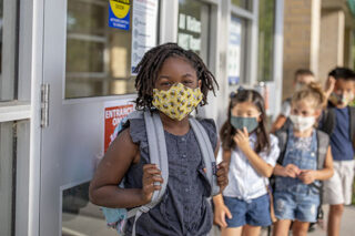 Diverse Group Of Elementary School Kids Go Back To School Wearing Masks