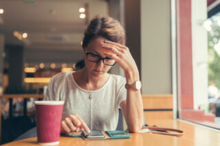 Woman In Cafe Stressed Looking At Phone