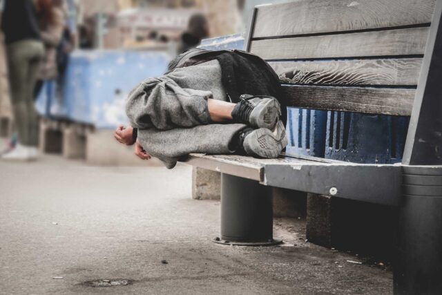 photo - homeless man sleeping on a bench