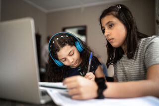 photo - Two Young Students Use Laptop for Schoolwork