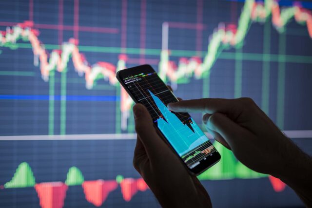 Hands With Cellphone And Economy Charts