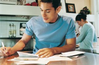 photo - Husband Paying Bills in Kitchen and Wife in Background