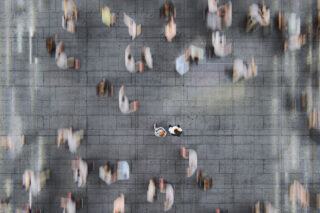 photo - Businessman Standing in the Fast Moving Crowds of Commuters