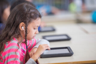 photo - Elementary age student working on tablet at table