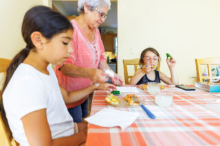 photo - Grandmother Serving Food to her Granddaughters at Dining Room Table