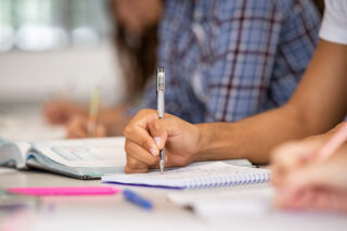photo - Student Hand Writing Notes in Classroom