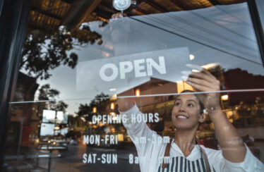Happy business owner hanging an open sign at a restaurant
