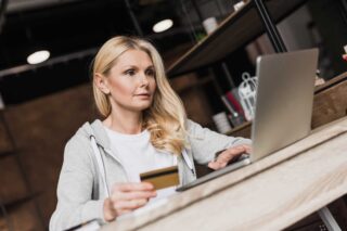 photo - Woman Holding Credit Card and Using Laptop at Home