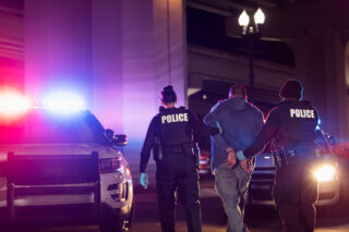 photo - Police with Handcuffed Suspect at Night
