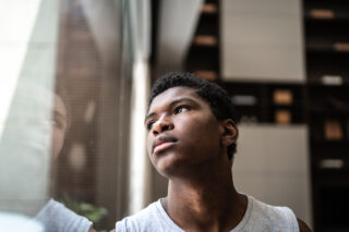photo - Teenage Boy Looking up and through Window
