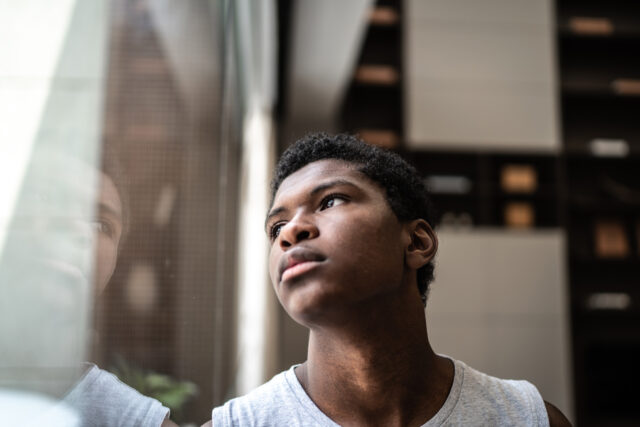photo - Teenage Boy Looking up and through Window