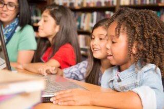 photo - elementary age children working with computers in school