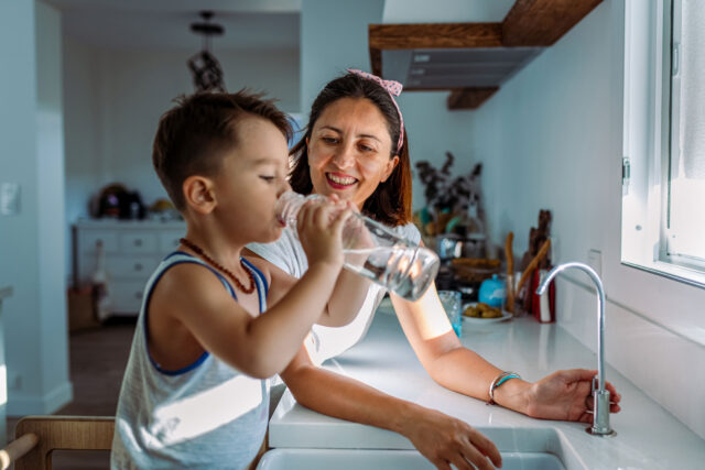 photo - Mother and her Toddler at Kitchen Sink Drinking Water