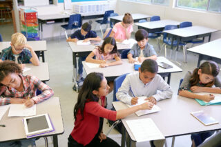 photo - Teacher with class of students with empty desks