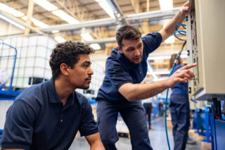 photo - Working engineers operating machines at manufacturing factory